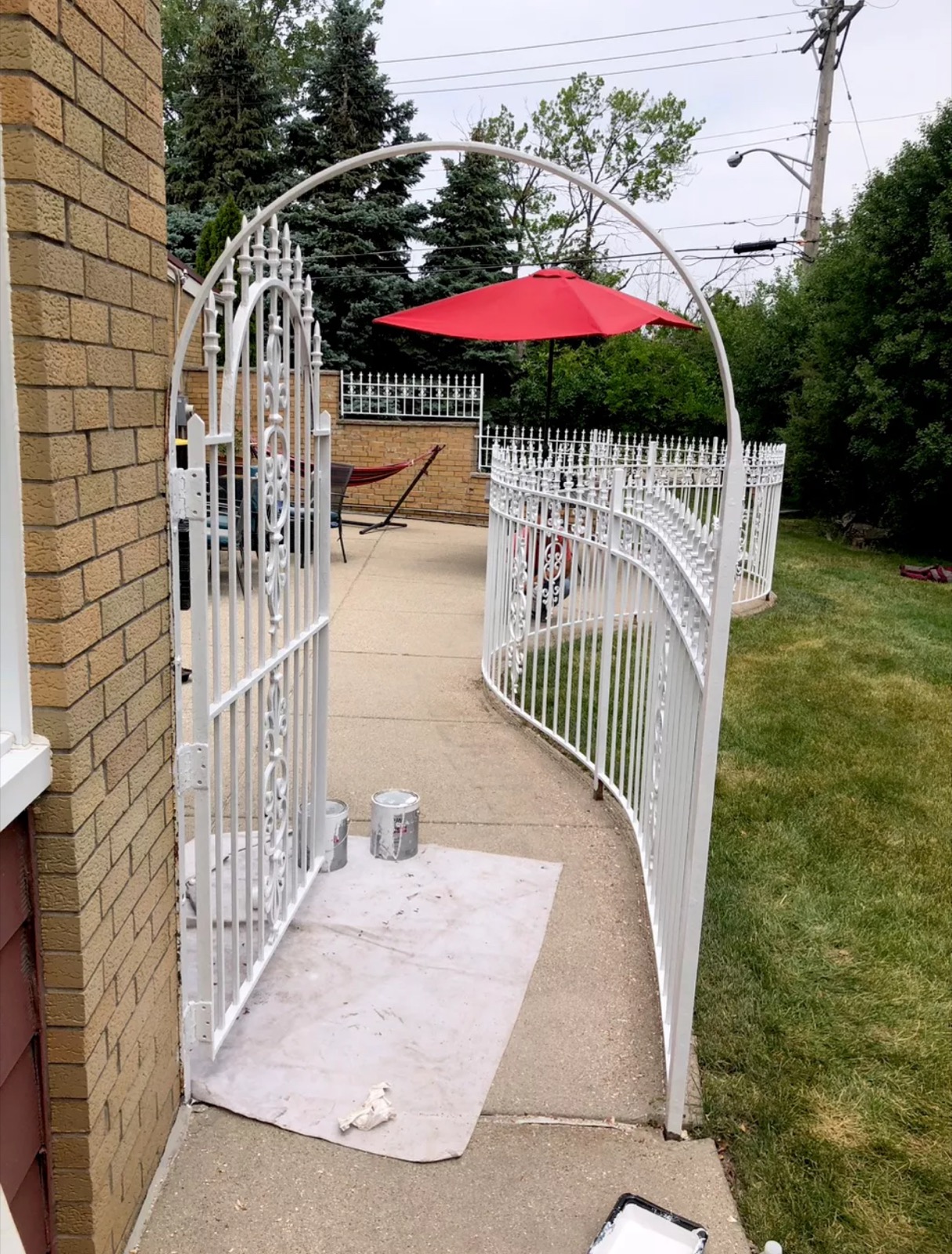 Decorative white ornamental gate with curved top opening into a residential patio area.