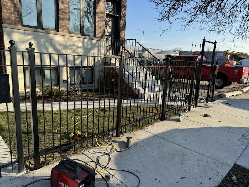 Finished black metal fence and gate line installed at a residential property.