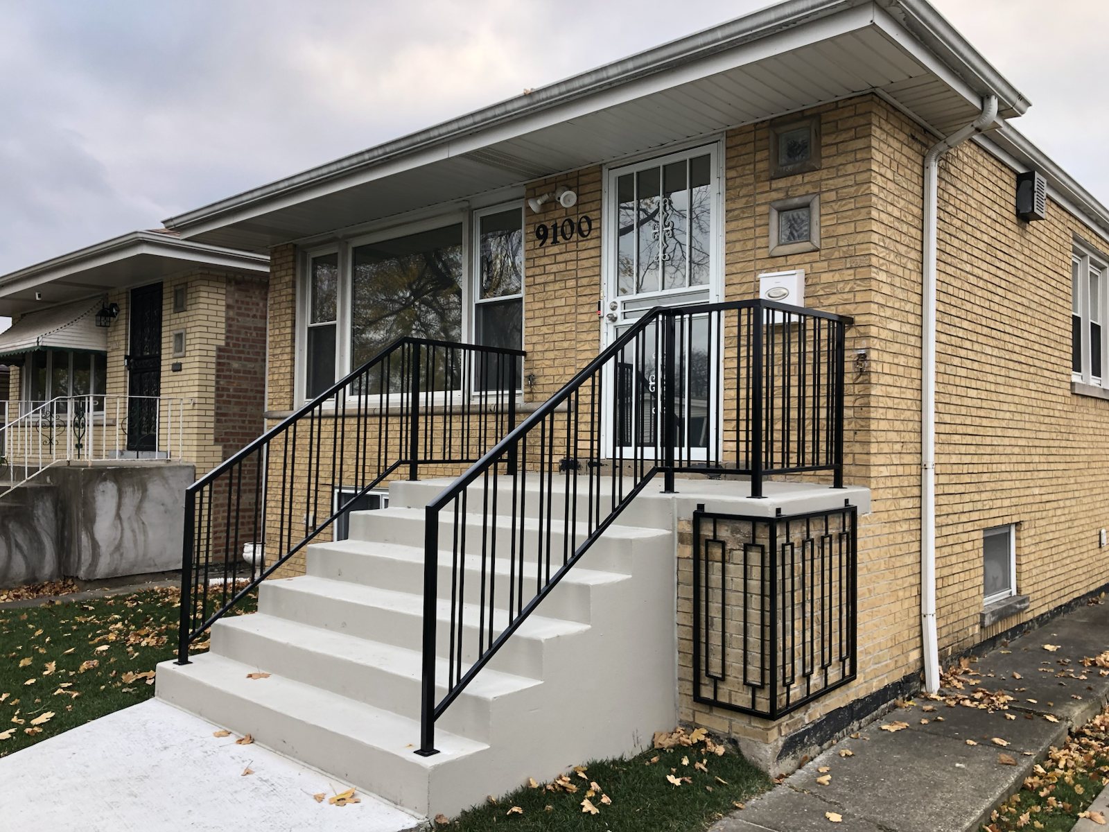 Black steel railings installed on refinished concrete front steps.