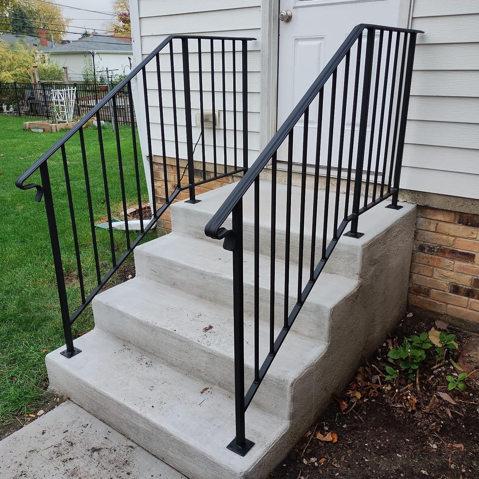 Dual black steel handrails installed on concrete front steps.