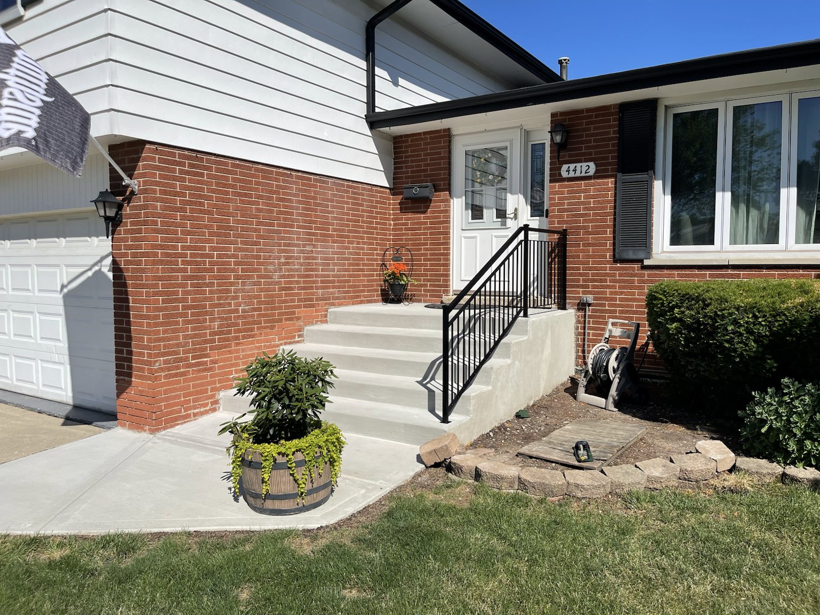 Black steel handrail installed on wide front steps at a brick Chicago-area home.