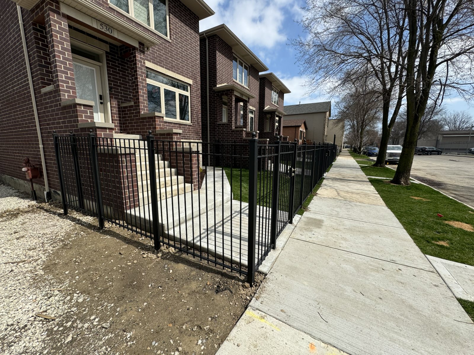 Black metal fence and front stair railings installed along a multiunit residential property.