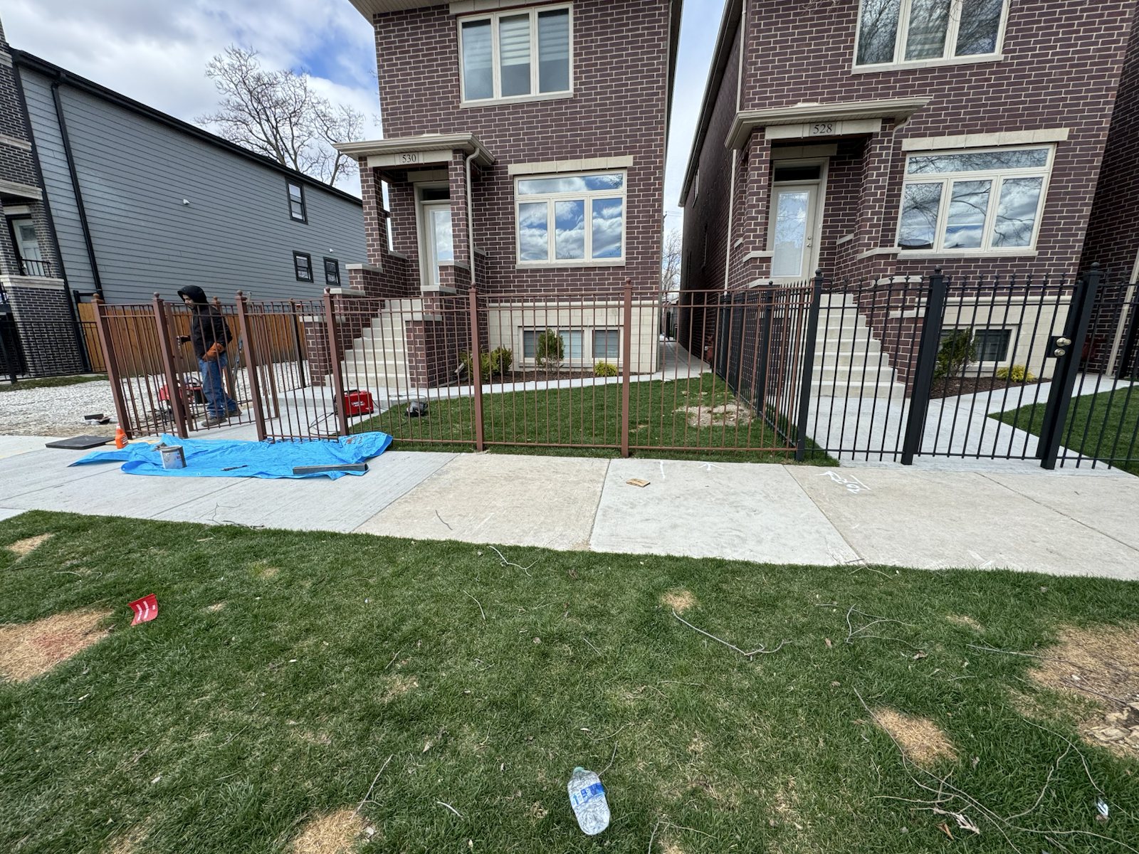 Metal fence and railing installation in progress at a multiunit residential frontage.