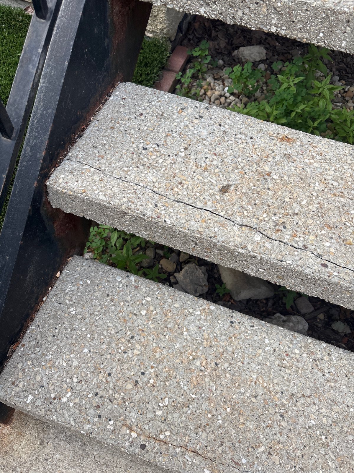 Cracked concrete stair tread on a steel front-step frame before repair.