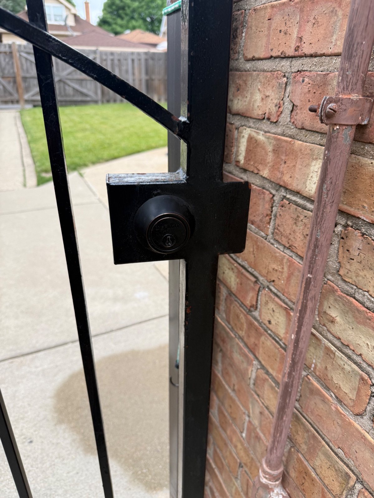 Close-up of a metal gate latch area before alignment and repair work.