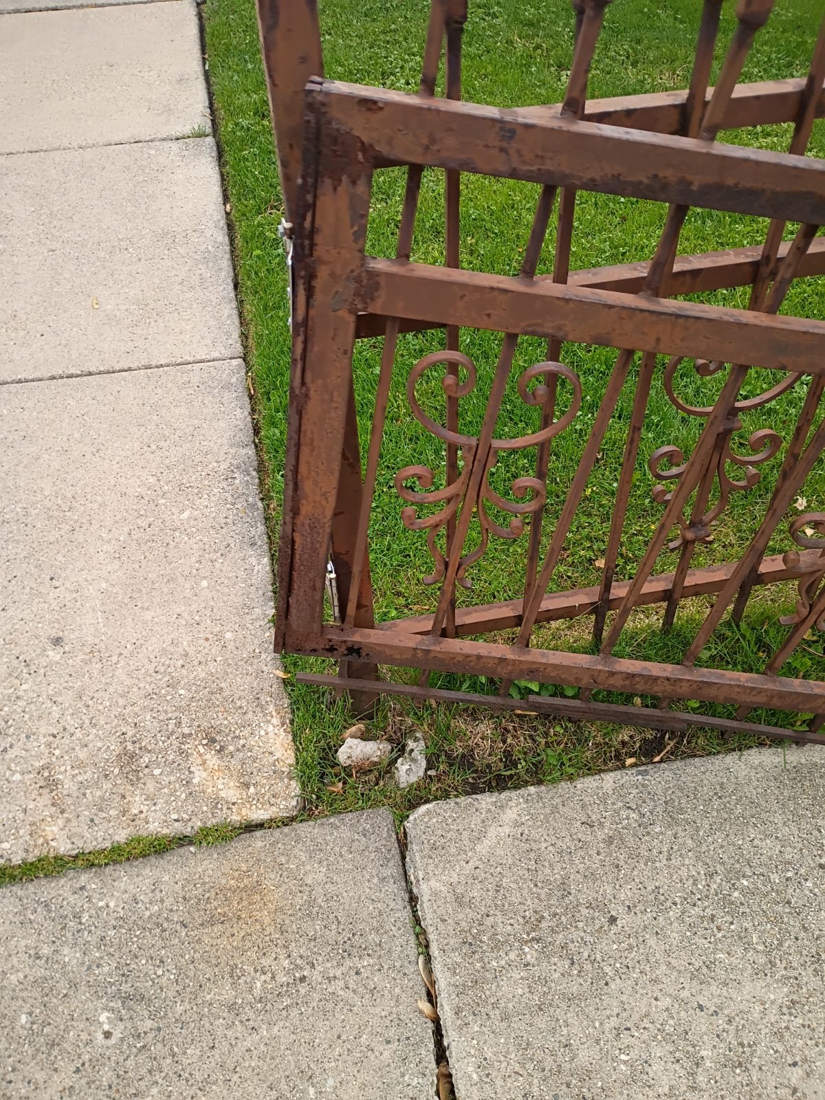Rusted pedestrian metal gate before repair and repaint planning.