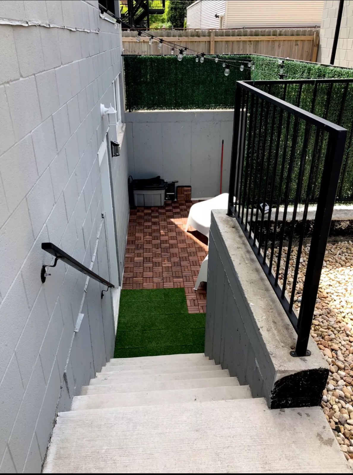 Black steel railing installed along a concrete walkout stair to a lower-level patio.