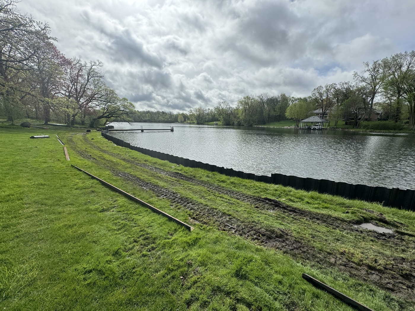 Long steel seawall and shoreline edge along a Chain O'Lakes style lake property before repair planning.