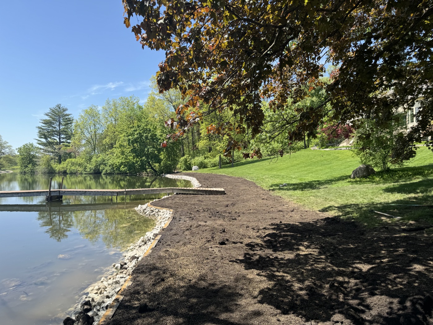 Finished shoreline grading with rip rap stone along a quiet lake edge.