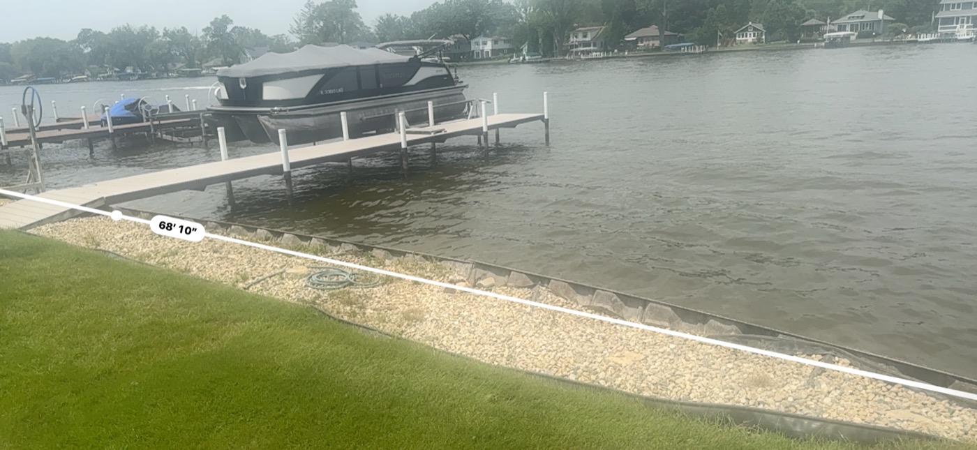 Lakefront seawall measurement photo showing a long shoreline span near docks and open water.