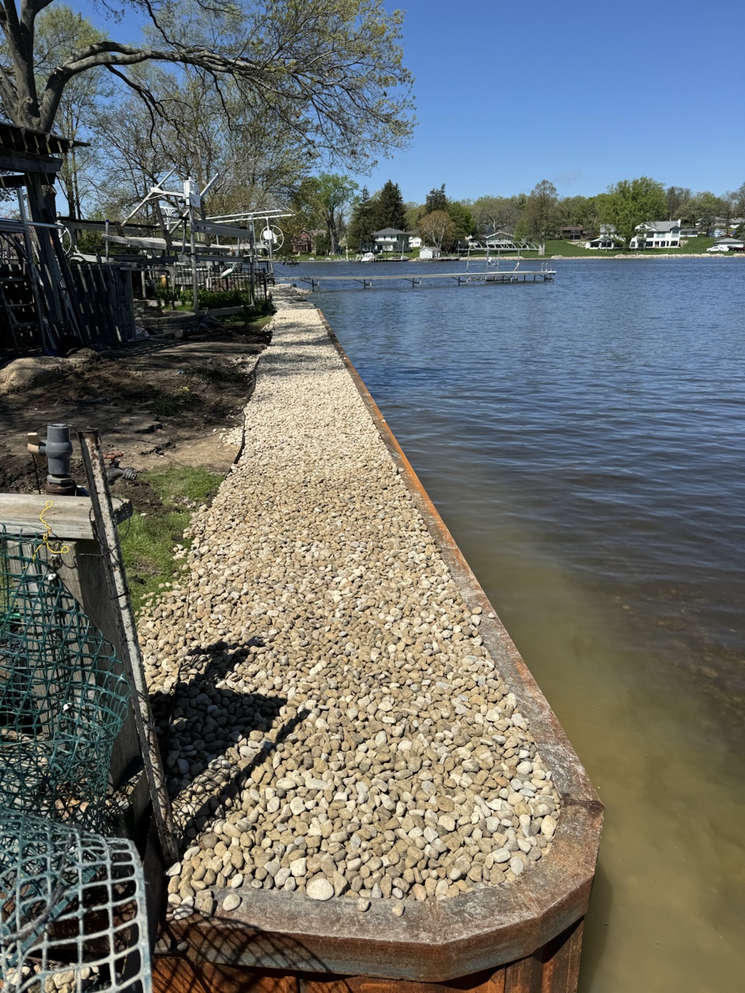 Lakefront steel wall with a finished rip rap stone edge and open water access.