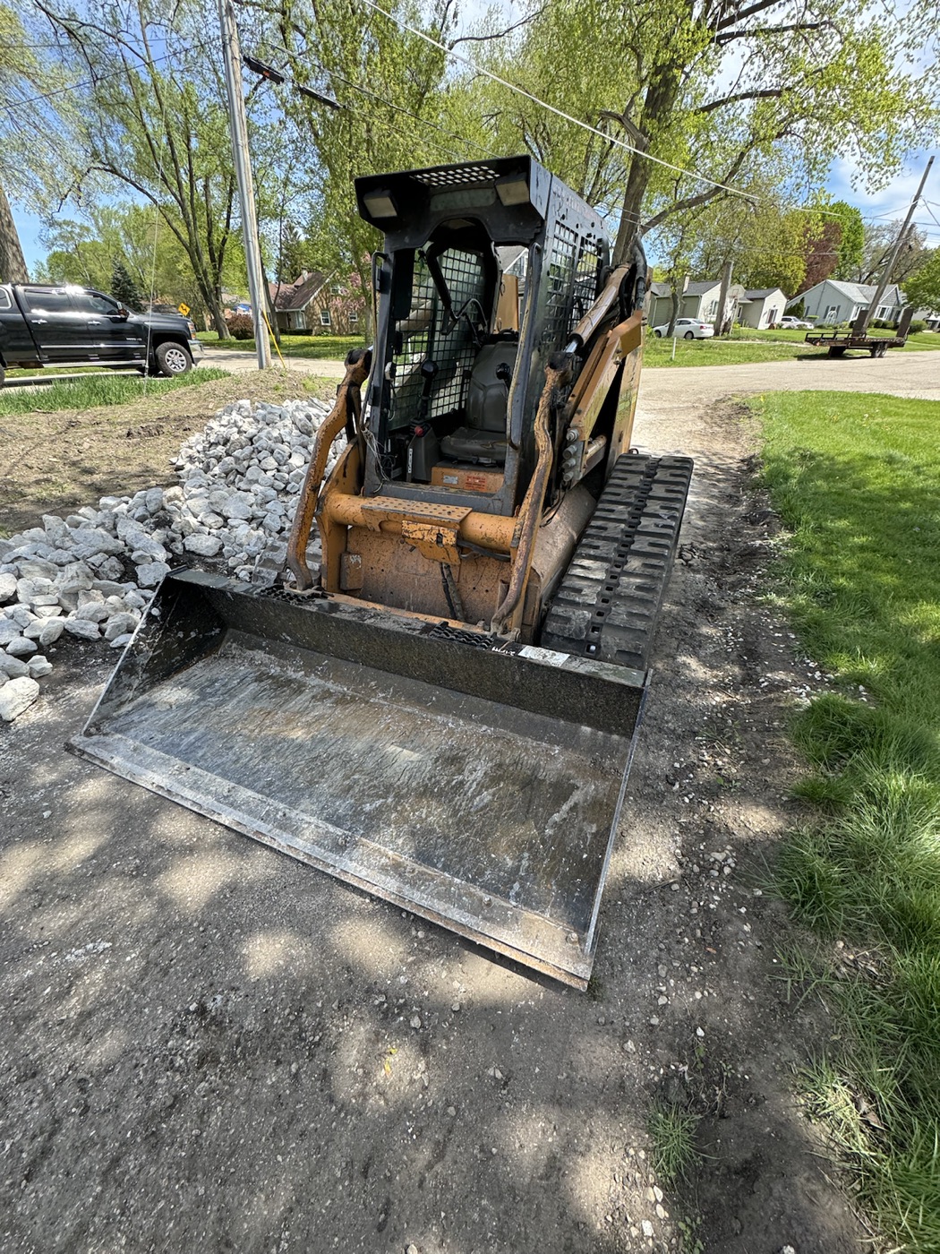 Skid steer staged near a shoreline project to show equipment access for seawall and rip rap work.