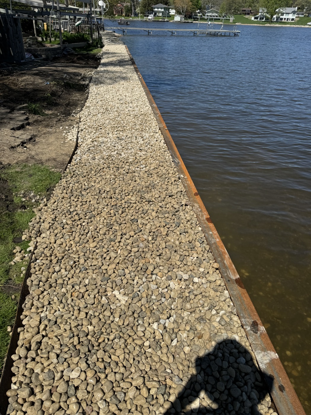 Steel seawall edge with rip rap stone placed along the waterline for shoreline protection.