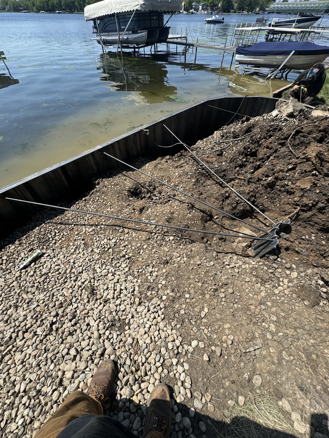 Steel seawall tie-back rods and shoreline structure exposed during repair planning.